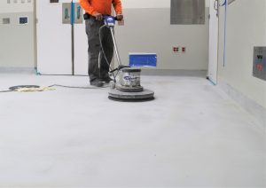 Construction worker grinding concrete floor